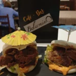 Dos baos rellenos de carne desmenuzada con salsa y lechuga, decorados con sombrillitas de cóctel.