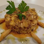 Plato presentado en un molde redondo, decorado con colines y perejil fresco.