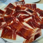 Plato de jamón ibérico cortado en finas lonchas y presentado en abanico.