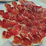 Plato de cecina curada en finas lonchas dispuestas en abanico.