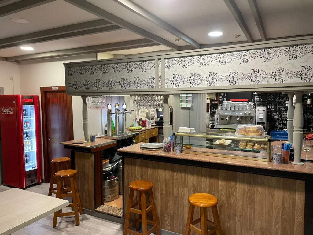Interior del Café de Mely en La Felguera, con barra, vitrinas de pinchos, cafetera profesional y zona de servicio.