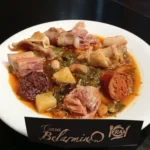 Plato de guiso asturiano con carne, chorizo, morcilla, patata y verdura servido en Casa Belarmino.